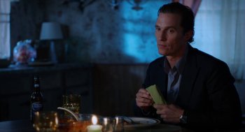 Movie still from “Killer Joe” (2011), directed by William Friedkin – A man sitting at a dinner table holding a piece of paper; Medium shot, Over the shoulder angle