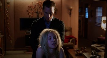 Movie still from “Killer Joe” (2011), directed by William Friedkin – A man standing next to a woman in a living room; Medium shot, Low angle