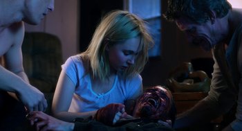 Movie still from “Killer Joe” (2011), directed by William Friedkin – A woman is looking at a zombie head; Medium shot, Over the shoulder angle