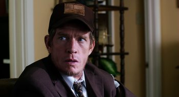 Movie still from “Killer Joe” (2011), directed by William Friedkin – A person wearing a suit and a hat; Close Up shot, Over the shoulder angle