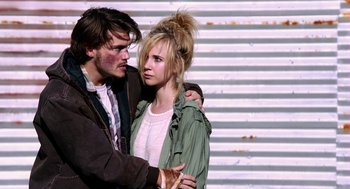Movie still from “Killer Joe” (2011), directed by William Friedkin – A man and a woman standing next to each other in front of a wall; Medium shot, Over the shoulder angle