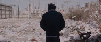 Movie still from “Killing Them Softly” (2012), directed by Andrew Dominik – A man standing in front of a pile of papers; Medium shot, Over the shoulder angle
