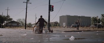 Movie still from “Killing Them Softly” (2012), directed by Andrew Dominik – A man walking a group of dogs down a street; Wide shot, Low angle