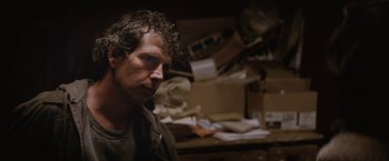 Movie still from “Killing Them Softly” (2012), directed by Andrew Dominik – A man in a messy room looking to his left; Close Up shot, Over the shoulder angle