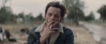 Movie still from “Killing Them Softly” (2012), directed by Andrew Dominik – A man smoking a cigarette while holding a cell phone to his mouth; Close Up shot, Low angle
