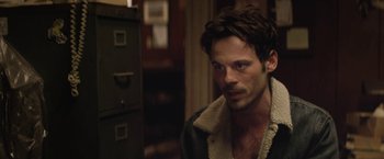 Movie still from “Killing Them Softly” (2012), directed by Andrew Dominik – A person wearing a jacket; Close Up shot, Over the shoulder angle