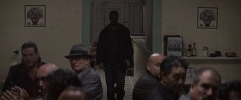 Movie still from “Killing Them Softly” (2012), directed by Andrew Dominik – A man walking down a hall way in a building; Wide shot, Over the shoulder angle