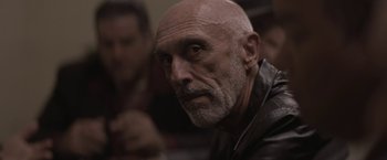 Movie still from “Killing Them Softly” (2012), directed by Andrew Dominik – An older man with a beard and a mustache; Close Up shot, Over the shoulder angle