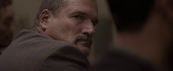 Movie still from “Killing Them Softly” (2012), directed by Andrew Dominik – A person wearing a suit and tie; Close Up shot, Over the shoulder angle