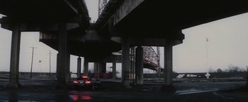 Movie still from “Killing Them Softly” (2012), directed by Andrew Dominik – A car driving under an overpass in the dark; Extreme Wide shot, Low angle