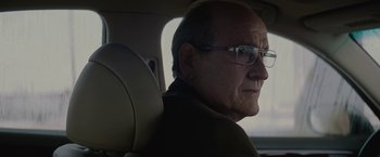 Movie still from “Killing Them Softly” (2012), directed by Andrew Dominik – An older man wearing glasses sitting in the back of a car; Close Up shot, Over the shoulder angle