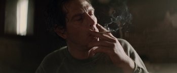 Movie still from “Killing Them Softly” (2012), directed by Andrew Dominik – A man is smoking a cigarette in a dark room; Close Up shot, Over the shoulder angle