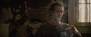 Movie still from “Killing Them Softly” (2012), directed by Andrew Dominik – A man is smoking a cigarette in a dark room; Close Up shot, Low angle