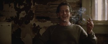Movie still from “Killing Them Softly” (2012), directed by Andrew Dominik – A man smiling with a cigarette in his mouth; Close Up shot, Low angle
