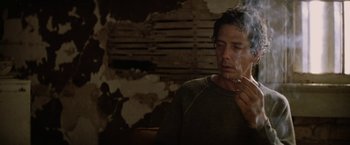 Movie still from “Killing Them Softly” (2012), directed by Andrew Dominik – A man smoking a cigarette while sitting in a room; Close Up shot, Low angle