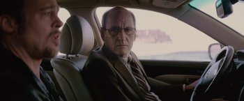 Movie still from “Killing Them Softly” (2012), directed by Andrew Dominik – An older man sitting in the back seat of a car; Close Up shot, Over the shoulder angle