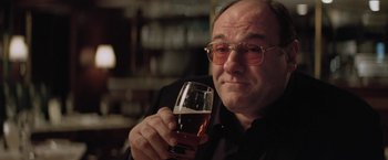 Movie still from “Killing Them Softly” (2012), directed by Andrew Dominik – A man holding a glass of beer while wearing glasses; Close Up shot, Low angle