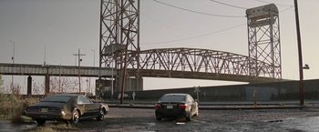 Movie still from “Killing Them Softly” (2012), directed by Andrew Dominik – A car parked on the side of the road under a bridge; Extreme Wide shot, Low angle