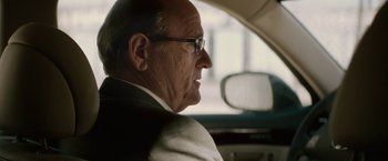 Movie still from “Killing Them Softly” (2012), directed by Andrew Dominik – An older man wearing glasses sitting in the back of a car; Close Up shot, Over the shoulder angle