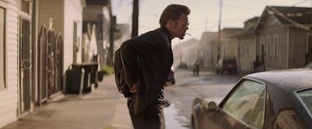 Movie still from “Killing Them Softly” (2012), directed by Andrew Dominik – A man smoking a cigarette on the side of the street; Medium shot, Low angle