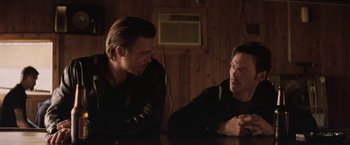 Movie still from “Killing Them Softly” (2012), directed by Andrew Dominik – A couple of men sitting next to each other at a table; Medium shot, Over the shoulder angle