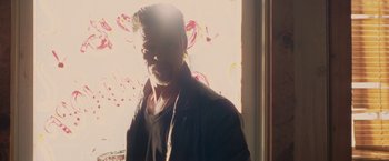 Movie still from “Killing Them Softly” (2012), directed by Andrew Dominik – A person standing near a window; Medium shot, Low angle