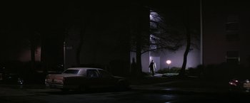 Movie still from “Killing Them Softly” (2012), directed by Andrew Dominik – A man standing next to a car on a street; Extreme Wide shot, Low angle
