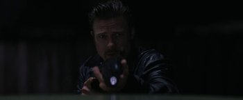 Movie still from “Killing Them Softly” (2012), directed by Andrew Dominik – A man in a leather jacket is holding a gun; Close Up shot, Over the shoulder angle