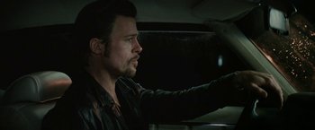 Movie still from “Killing Them Softly” (2012), directed by Andrew Dominik – A man driving a car at night in the dark; Close Up shot, Over the shoulder angle