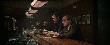 Movie still from “Killing Them Softly” (2012), directed by Andrew Dominik – A group of people sitting at a bar; Wide shot, Over the shoulder angle