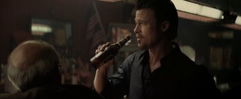Movie still from “Killing Them Softly” (2012), directed by Andrew Dominik – A man is holding a bottle of beer in his hand; Close Up shot, Over the shoulder angle