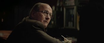 Movie still from “Killing Them Softly” (2012), directed by Andrew Dominik – An older man sitting at a table with a glass of wine; Close Up shot, Over the shoulder angle