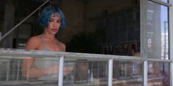 Movie still from “Kimi” (2022), directed by Steven Soderbergh – A woman with blue hair standing in front of a window; Medium shot, High angle