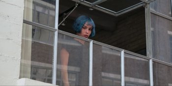 Movie still from “Kimi” (2022), directed by Steven Soderbergh – A woman with blue hair looking out of a window; Medium shot, High angle
