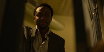 Movie still from “Kimi” (2022), directed by Steven Soderbergh – A man wearing a suit and a white shirt; Close Up shot, Low angle