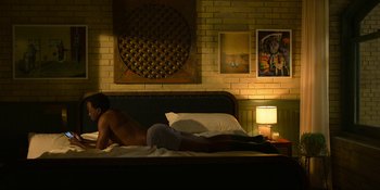 Movie still from “Kimi” (2022), directed by Steven Soderbergh – A man laying on a bed in front of a lamp; Wide shot, Overhead angle