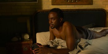 Movie still from “Kimi” (2022), directed by Steven Soderbergh – A man laying on a bed holding a cell phone; Medium shot, High angle