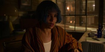 Movie still from “Kimi” (2022), directed by Steven Soderbergh – A woman with blue hair sitting in front of a window at night; Medium shot, Over the shoulder angle