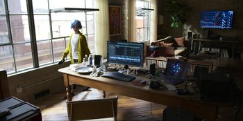 Movie still from “Kimi” (2022), directed by Steven Soderbergh – A person standing in front of a computer on a desk; Wide shot, High angle