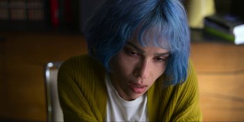 Movie still from “Kimi” (2022), directed by Steven Soderbergh – A person with blue hair is sitting in a room; Close Up shot, High angle