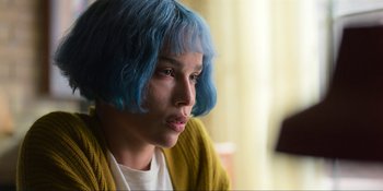 Movie still from “Kimi” (2022), directed by Steven Soderbergh – A person with blue hair is sitting in a room; Close Up shot, Over the shoulder angle