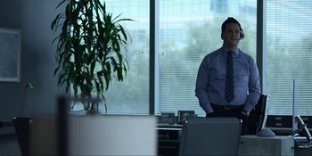 Movie still from “Kimi” (2022), directed by Steven Soderbergh – A man standing in front of a window in an office setting; Medium shot, Over the shoulder angle
