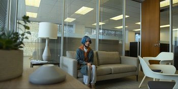 Movie still from “Kimi” (2022), directed by Steven Soderbergh – A person sitting on a couch in a room; Wide shot, High angle