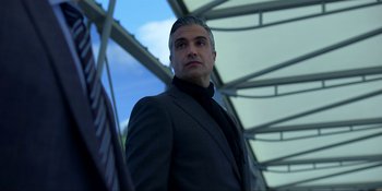 Movie still from “Kimi” (2022), directed by Steven Soderbergh – A man in a suit and tie standing in front of a building; Close Up shot, Low angle