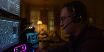 Movie still from “Kimi” (2022), directed by Steven Soderbergh – A man wearing a headset looking at a computer screen; Medium shot, Over the shoulder angle