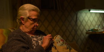 Movie still from “Kimi” (2022), directed by Steven Soderbergh – An older woman is sewing on a pillow; Close Up shot, High angle