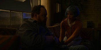 Movie still from “Kimi” (2022), directed by Steven Soderbergh – A man and a woman sitting on a couch in a room; Medium shot, Over the shoulder angle