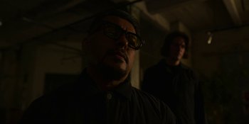 Movie still from “Kimi” (2022), directed by Steven Soderbergh – A man wearing glasses and a hat is looking at the camera; Close Up shot, Over the shoulder angle