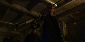 Movie still from “Kimi” (2022), directed by Steven Soderbergh – A man in a black suit holding a gun in a room; Medium shot, Low angle