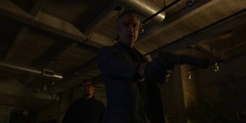 Movie still from “Kimi” (2022), directed by Steven Soderbergh – A man holding a gun in a dark room; Medium shot, Low angle